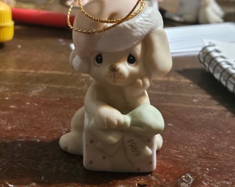 May include: A porcelain figurine of a dog wearing a Santa hat and holding a gift box with the year 1989 on it.