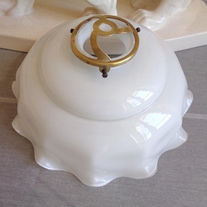 May include: A white glass lampshade with a ruffled edge and a brass-toned metal fitting. The lampshade is a rounded shape. The metal fitting has a decorative design.
