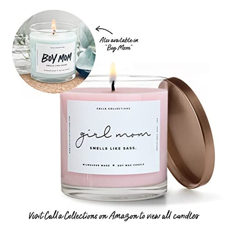 Pu&ograve; includere: Una candela di cera di soia rosa in un barattolo di vetro trasparente con un'etichetta bianca che recita "Calla Collections girl mom SMELLS LIKE SASS. MILWAUKEE MADE SOY WAX CANDLE". La candela &egrave; su una superficie bianca con un coperchio dorato.