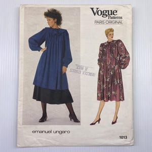 Könnte beinhalten: Vogue Patterns Schnittmuster mit zwei Kleiderdesigns. Ein Kleid ist ein blaues Kleid mit langen Ärmeln, Rüschenkragen und schwarzem Rock. Das andere Kleid ist ein Kleid mit floralem Muster und langen Ärmeln. Das Muster ist mit "emanuel ungaro" und "1013" gekennzeichnet.