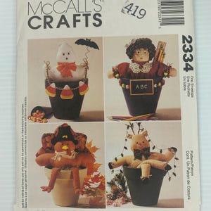 May include: A McCall's Crafts pattern envelope featuring four craft projects. The projects include a ghost, a teacher, a turkey, and a reindeer, all in decorative pots. The envelope has the number 2334 and the text "One Envelope".