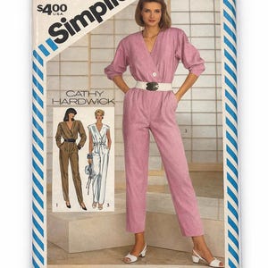 Può includere: Cartamodello Simplicity per una tuta rosa. Il modello mostra una donna che indossa la tuta, con il testo "Cathy Hardwick". Il modello è taglia N (10-12-14). Il pacchetto include anche altri modelli.