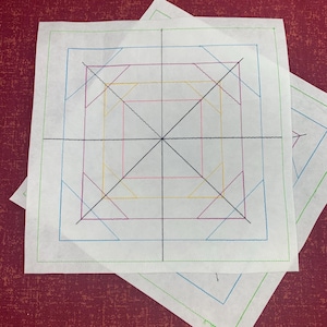 May include: Two white pieces of paper with a grid pattern drawn on them in black, green, blue, yellow, and pink lines. The grid pattern is a square with lines extending from the center to each corner and side.