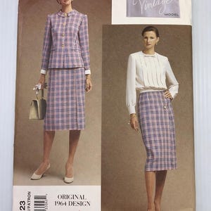 May include: Vogue Vintage Model sewing pattern showing a two-piece suit and a skirt. The suit is a pink and blue plaid with gold buttons. The skirt is a matching plaid. The pattern is an original 1964 design.