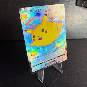 Op de afbeelding: Een holografische Pokémon-verzamelkaart met Flying Pikachu VMAX. De kaart is blauw en geel met een afbeelding van Pikachu in het midden. De kaarttekst luidt "VMAX Flying Pikachu VMAX 3100" en "Max Balloon 160".