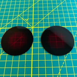 Puede incluir: Dos dianas circulares negras con un patr&oacute;n de cuadr&iacute;cula roja.