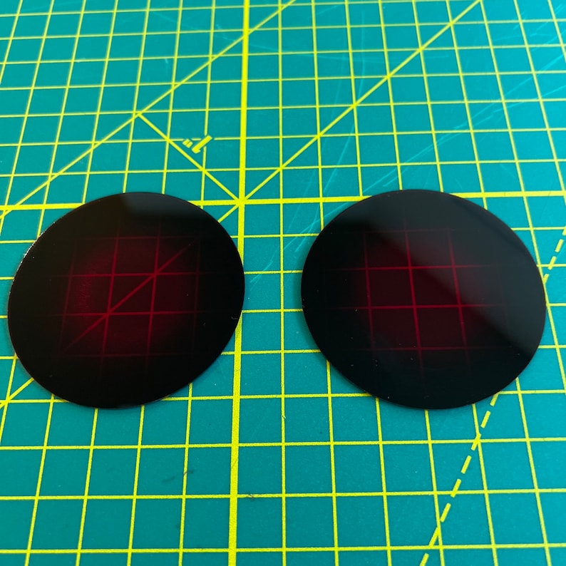 Puede incluir: Dos dianas circulares negras con un patr&oacute;n de cuadr&iacute;cula roja.