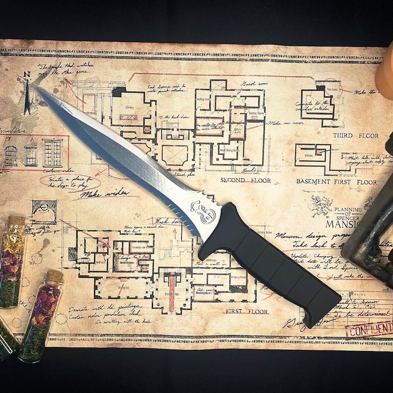 May include: A silver and black tactical knife with a serrated blade and a black handle. The knife is lying on a map with a floor plan of a mansion. The map is labeled "Planning of Spencer Mansion".