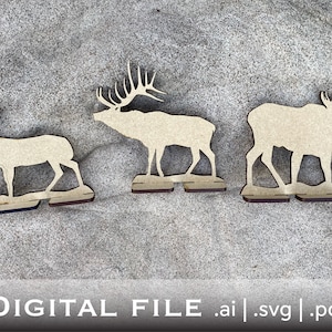 May include: Three wooden cutout animal silhouettes on a beige background. The animals are a deer, an elk, and a moose. The animals are all facing the right side of the image. The deer is in the front, the elk is in the middle, and the moose is in the back.