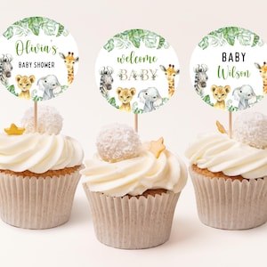 May include: Three cupcakes decorated with round, white, paper toppers featuring jungle animal illustrations and the text "Olivia's Baby Shower", "Welcome Baby", and "Baby Wilson".