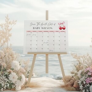 May include: A white calendar with a pink and white border, with the text "Guess The Birth Date of Baby Wilson" at the top. The calendar is for December and January, with the due date marked on January 17th. Two red cherries with a pink ribbon are in the top right corner.
