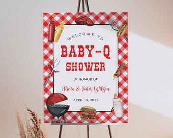 Puede incluir: Un letrero a cuadros rojos y blancos sobre un caballete, que anuncia un "BABY-Q SHOWER" en texto rojo. El letrero incluye ilustraciones de artículos relacionados con la barbacoa, como una parrilla, una hamburguesa y un perrito caliente. La fecha del evento es el 15 de abril de 2025.