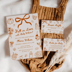 May include: Baby shower invitation set with a fall theme. The invitation features the text "Fall in Love with Baby Wilson!" and includes a diaper raffle and books for baby cards. The design includes illustrations of pumpkins, bows, and food items.