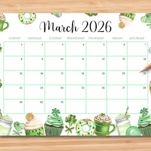 May include: A March 2026 calendar with a green grid, featuring St. Patrick's Day themed illustrations. The calendar includes images of cupcakes, donuts, and drinks with shamrock and gold coin accents. The calendar is on a wooden surface.