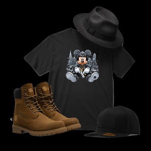 Puede incluir: Una camiseta negra con un gr&aacute;fico de Mickey Mouse con una cadena de oro y sosteniendo una pistola. El gr&aacute;fico est&aacute; sobre un fondo de paisaje urbano. La camiseta se combina con botas de cuero marr&oacute;n, un sombrero fedora negro y una gorra de b&eacute;isbol negra.
