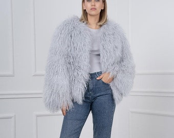 May include: A woman wearing a light gray fluffy jacket, blue jeans, and black platform shoes.
