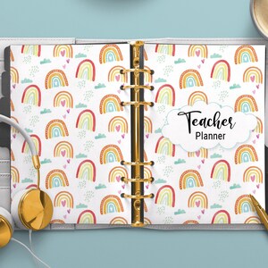 May include: A white teacher planner with a rainbow and heart pattern. The cover says "Teacher Planner" in black text.