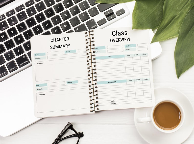 May include: An open spiral bound notebook with two sections, one labeled "Chapter Summary" and the other labeled "Class Overview". The notebook is on a white surface with a laptop, a cup of coffee, and a pair of glasses.