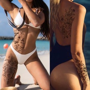 May include: Two women with temporary tattoos on their bodies. One woman has a floral tattoo on her thigh and stomach. The other woman has a floral tattoo on her upper arm and back.