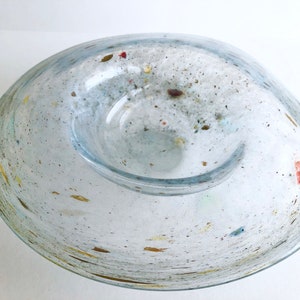 May include: A clear glass bowl with a speckled, frosted finish. The bowl has a wide, shallow base and a smaller, deeper inner bowl. The bowl is decorated with flecks of gold, red, and blue.