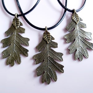 May include: Three necklaces with bronze oak leaf pendants on black cords. The leaves have a detailed, textured design.