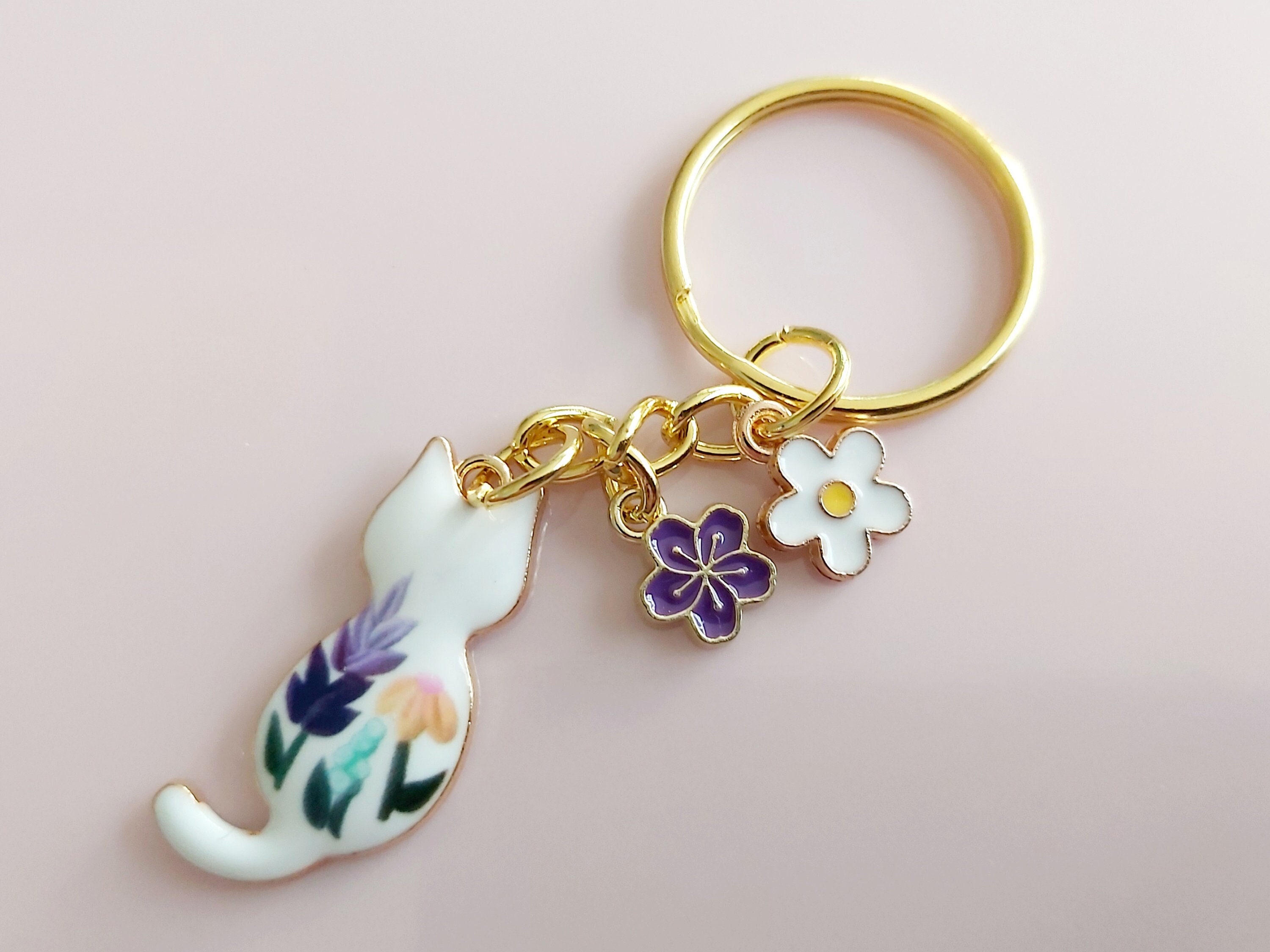 White flower cat keyring. Small enamel feline floral charm with daisy and sakura flowers. Gold tone split keychain for cat & garden lovers.