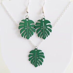May include: A green monstera leaf necklace and earrings set. The necklace features a single leaf pendant and the earrings are dangle style with a leaf design.
