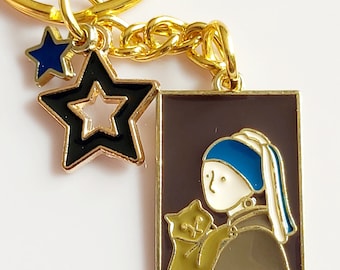 Hidden cat art keyring. Girl with a pearl earring with cat. Brown background and blue & black stars. Enamel charms on gold tone keychain.