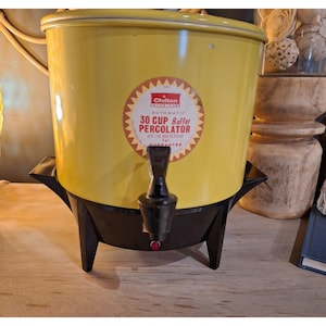 May include: A vintage yellow Chilton 30-cup buffet percolator with a black base and spout. The percolator has a red and white label that reads "Chilton Automatic 30 Cup Buffet Percolator". The appliance is designed for brewing coffee.
