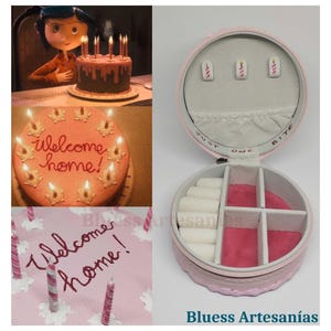 May include: A pink, round jewellery box with multiple compartments, open to reveal storage for rings and earrings. The box is next to images of cakes with lit candles and the words "Welcome home!" written on them. The text "Bluess Artesan&iacute;as" is at the bottom.