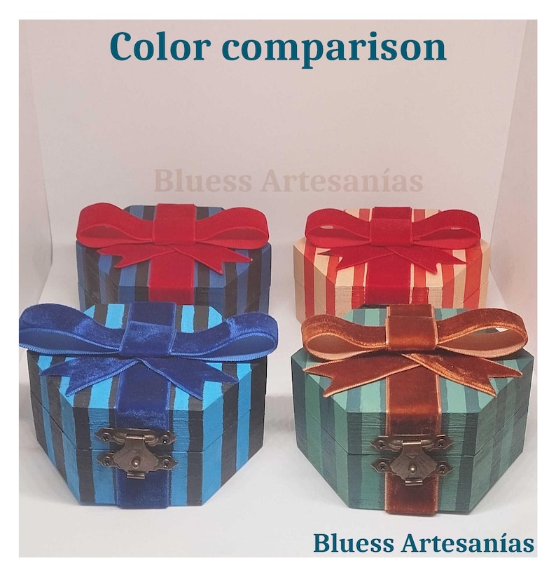 Op de afbeelding: Vier decoratieve, zeshoekige dozen met streepjespatronen en fluwelen strikken. De dozen zijn in blauwe, rode en groene tinten, met messingkleurige sluitingen. De tekst "Color comparison" en "Bluess Artesan&iacute;as" is zichtbaar.