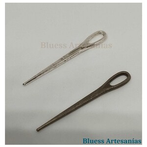 Op de afbeelding: Twee metalen splitpennen, &eacute;&eacute;n zilverkleurig en &eacute;&eacute;n bronskleurig, worden getoond tegen een lichte achtergrond. De pennen hebben een lus aan &eacute;&eacute;n uiteinde en een punt aan het andere. De tekst "Bluess Artesan&iacute;as" is zichtbaar.