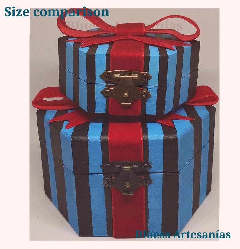 May include: Two hexagonal wooden boxes, one on top of the other, painted with blue and black vertical stripes. Each box has a red ribbon and bow, with a brass clasp closure. The text "Size comparison" is visible.