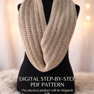 Puede incluir: Bufanda infinita beige tejida a ganchillo, exhibida en un maniquí negro. La bufanda está hecha de un hilo texturizado y está drapeada en forma de ocho. El texto en la imagen dice "DIGITAL STEP-BY-STEP PDF PATTERN".
