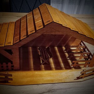 May include: A wooden nativity scene with a brown roof and a manger inside. The scene is made of wood and has a rustic look.
