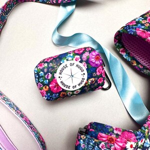 Puede incluir: Un juego de correa y collar para perro con estampado floral y un porta bolsas para excrementos a juego. El porta bolsas para excrementos tiene un c&iacute;rculo blanco con el texto "House of Hugo" y un dise&ntilde;o de br&uacute;jula.