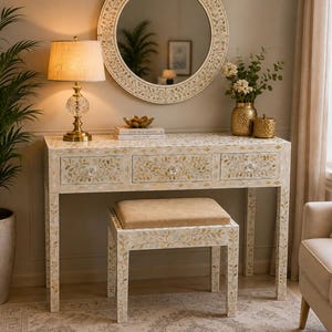 Op de afbeelding: Een rechthoekige consoletafel en bijpassende kruk met een ingewikkeld crème- en goudkleurig bloemenpatroon. De tafel heeft drie lades met heldere kristallen knoppen en de kruk heeft een beige gestoffeerde zitting. Beide hebben rechte poten.