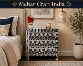 May include: A three-drawer nightstand featuring a black and white geometric floral inlay pattern. The piece has a rectangular top, straight legs, and small white knobs on each drawer. The text Mehar Craft India is visible at the top of the image.
