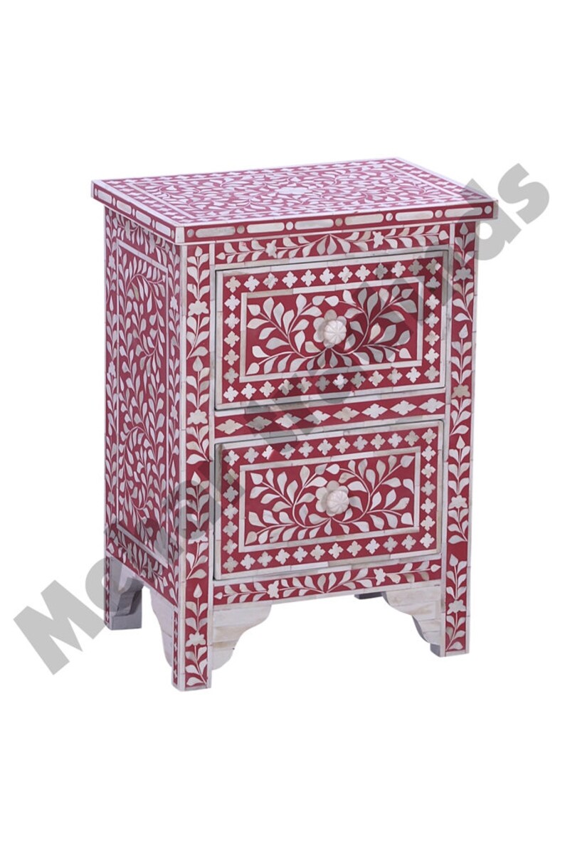 May include: A red wooden nightstand with two drawers, both decorated with white floral patterns and bone inlay. The nightstand has a floral design on the front and sides.