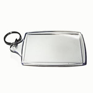 May include: A clear plastic keyring with a rectangular frame for inserting a photo or other small item. The keyring has a silver metal ring.