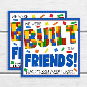 Puede incluir: Una tarjeta de San Valentín con un borde azul y un diseño de bloques de Lego coloridos. La tarjeta dice "We were built to be friends!" y "Happy Valentine's Day! From: Janell Williamson".