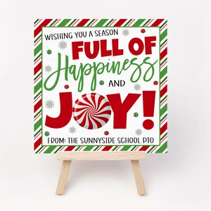 K&ouml;nnte beinhalten: Ein wei&szlig;es Schild mit roten und gr&uuml;nen Streifen um den Rand. Das Schild sagt "Wishing you a season full of happiness and joy!" mit einer Zuckerstangengrafik. Das Schild sagt auch "From: The Sunnyside School PTO".