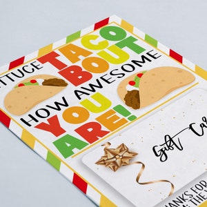 Op de afbeelding: Een witte kaart met een kleurrijke rand en de tekst "Lettuce Taco Bout How Awesome You Are!" met twee cartoon-tacos. De kaart heeft ook een cadeaukaartsectie met de tekst "Gift Card" en een gouden strik.