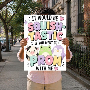 May include: A white sign with the text "IT WOULD BE SQUISH-TASTIC IF YOU WENT TO PROM WITH ME" in pastel colors. The sign features illustrations of a cow, frog, and penguin. The sign is held by a person.