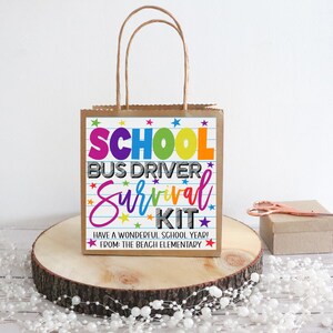 K&ouml;nnte beinhalten: Eine braune Papiert&uuml;te mit einem bunten bedruckten Etikett, auf dem "School Bus Driver Survival Kit" und "Have a Wonderful School Year! From: The Beach Elementary" steht.