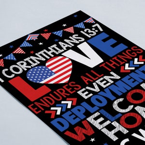 May include: A black and white sign with red, white, and blue accents. The sign features the text "I Corinthians 13:7 Love Endures All Things Even Deployments Welcome Home" with a heart-shaped American flag in the center.