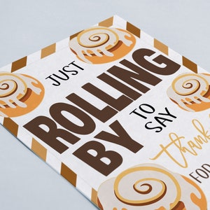May include: A white card with brown and gold stripes. The card has a cinnamon roll design and the text "Just rolling by to say thank you for everything that you do".