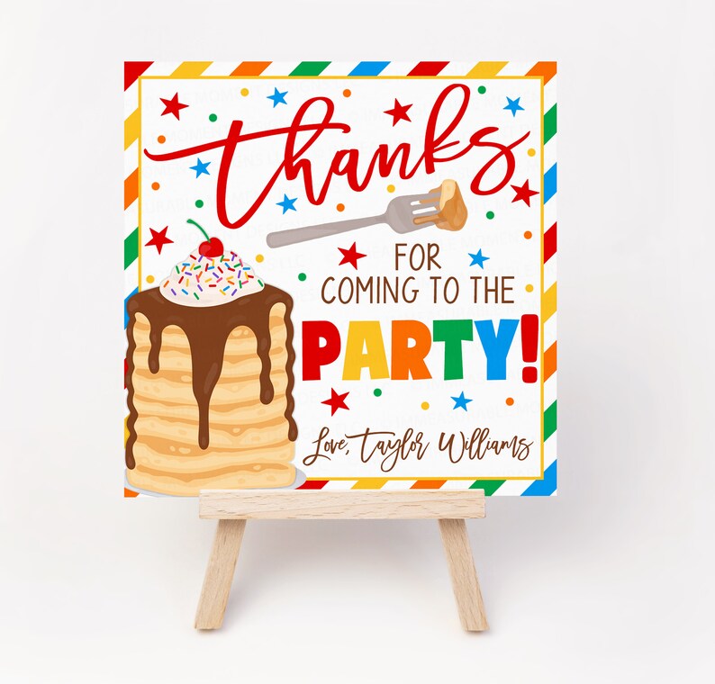 May include: A square party sign on a small wooden easel. The sign features the word "thanks" in red script, a stack of pancakes with chocolate syrup, and the text "For coming to the party!"
