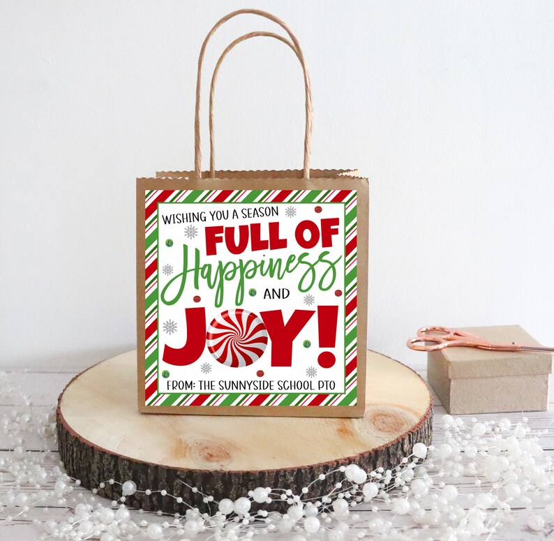 K&ouml;nnte beinhalten: Eine rot-gr&uuml;ne gestreifte Geschenkt&uuml;te mit einem wei&szlig;en Etikett, auf dem "Wishing you a season full of happiness and joy!" mit einer Zuckerstangengrafik steht. Das Etikett tr&auml;gt au&szlig;erdem den Text "From: The Sunnyside School PTO".