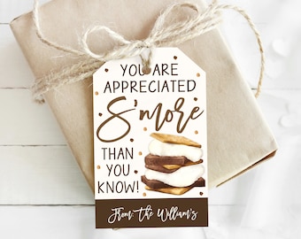 Może przedstawiać: Biała etykieta prezentowa z brązowym tekstem, który brzmi "You are appreciated s'more than you know!" z brązową i białą ilustracją s'more. Dolna część etykiety ma brązowy tekst, który brzmi "From: The Williams'"